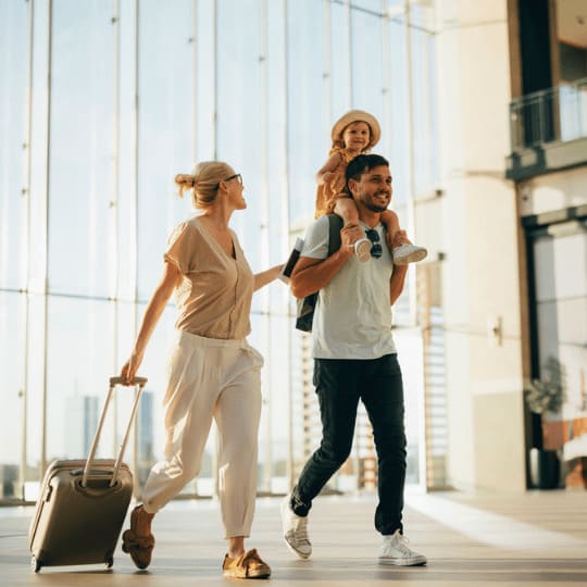 famille souriante avec valise dans un aéroport, voyage facilité grâce aux visas en règle