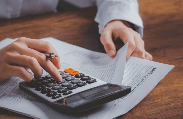 Person using a calculator to calculate taxes on fiscal documents